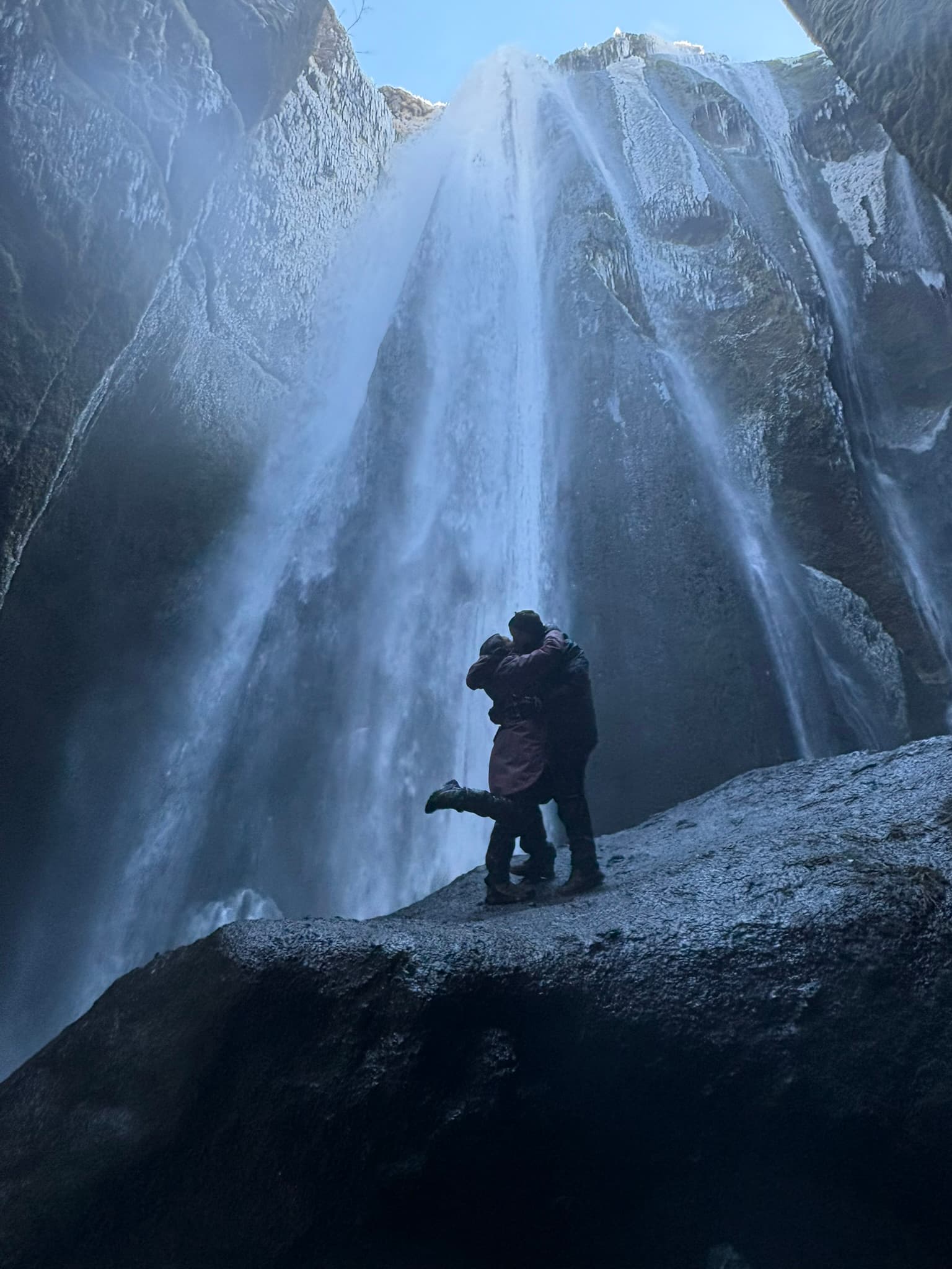 Cristina y Eugenio se abrazan junto a una cascada durante uno de sus viajes